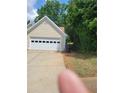 Attached garage with a white door and a concrete driveway, next to lush greenery at 1150 Hillary Ln, Lawrenceville, GA 30043