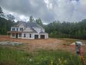 Unfinished two-story home with visible framework and a lush green backdrop showcases potential at 3301 Lions Ruby Ln, Atlanta, GA 30349