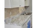 Close-up on kitchen marble countertops with a chrome faucet and a tiled backsplash at 6354 Shannon Pkwy # 20D, Union City, GA 30291