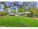 Scenic view of ranch home featuring a lush green lawn, mature trees, and manicured landscaping at 1155 Moores Mill Nw Rd, Atlanta, GA 30327