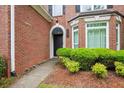 Close-up of the home's front entrance, showcasing a black door, brick facade, and green shrubbery at 1187 Druid Walk, Decatur, GA 30033
