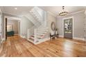 Bright foyer features hardwood floors, a staircase with white railings, and elegant lighting fixtures at 230 Pebble Trl, Alpharetta, GA 30009