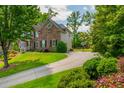 Long driveway leads to a beautiful brick home surrounded by lush landscaping and mature trees at 7048 Bennington Ln, Cumming, GA 30041