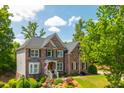 Brick home with black shutters complemented by a green lawn and mature trees on a sunny day at 7048 Bennington Ln, Cumming, GA 30041