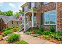 Charming brick home with a welcoming front porch, complete with an American flag and lush landscaping at 7048 Bennington Ln, Cumming, GA 30041