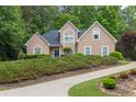 Attractive tan home with a dark roof, showcasing a meticulously maintained front yard with shrubbery at 1720 Ivey Trce, Cumming, GA 30041