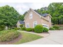 Side view of a two-story tan home, highlighting the attached garage and mature greenery at 1720 Ivey Trce, Cumming, GA 30041