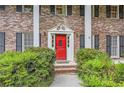 Charming brick home entrance with a bright red door, flanked by greenery and black shutters at 2034 Starfire Ne Dr, Atlanta, GA 30345