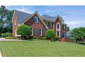 Classic brick home with meticulous landscaping showcasing a well-groomed lawn and mature trees, adding to its allure at 3331 Lockwood Sw Ct, Lilburn, GA 30047