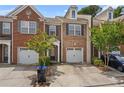 Charming brick townhouse with an attached garage, mature landscaping and front yard parking spaces at 1880 Garbrooke Cv, Lawrenceville, GA 30046
