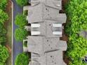 Overhead view of townhome roofs with dormer windows, lush trees, and nearby road at 11187 Calypso Dr # 12, Alpharetta, GA 30009