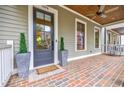 Inviting front porch boasts brick flooring and a view of the landscaped front yard at 1076 Green St, Roswell, GA 30075