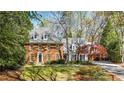 Traditional brick home with a manicured lawn, mature trees, and a charming porte-cochere at 1285 Wesley Nw Pl, Atlanta, GA 30327