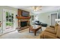Cozy living room boasts a brick fireplace, ceiling fan, and door to the outdoor space at 4730 Geneva Sw Dr, Lilburn, GA 30047