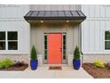 Inviting front door features an orange door, sidelights, and decorative potted plants at 4840 Moon Rd, Powder Springs, GA 30127