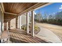 Covered porch with stone wall, white pillars, wood ceiling and decking, and verdant landscaping at 121 Harmony Oaks Trl, Canton, GA 30115