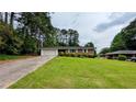 Charming brick home with a well-manicured lawn and a long driveway leading to an attached garage at 1091 Luther Sw Dr, Mableton, GA 30126
