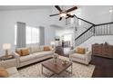 Bright living room featuring a high ceiling, fan, staircase, hardwood floors, and comfortable neutral furniture at 1468 Briarwood Ne Rd # 2003, Atlanta, GA 30319