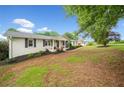 Landscaped front yard with a white brick house, classic architectural details, and mature trees at 3415 Trickum Rd, Woodstock, GA 30188