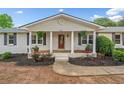 Beautiful white brick house with a red front door, covered porch, and meticulously landscaped yard at 3415 Trickum Rd, Woodstock, GA 30188