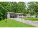 View of the house exterior with a long driveway and carport amid lush greenery at 2585 Whisper Trail, Douglasville, GA 30135