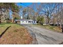 Long driveway leading up to a cozy home with a carport and front porch, surrounded by trees at 1766 Blossom Ln, Austell, GA 30168