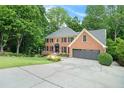 Two story brick home with mature trees and an expansive concrete driveway at 5020 Huntshire Sw Ln, Lilburn, GA 30047