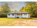 Single-story home featuring a cozy front porch, crisp gray siding, and a well-kept lawn with mature trees in the background at 4665 Jersey Walnut Grove Rd, Covington, GA 30014