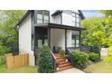 Inviting covered front porch with stylish railings, steps, seating, and lush landscaping at 1676 Carroll Nw Dr, Atlanta, GA 30318