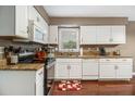 Bright kitchen featuring white cabinets, granite countertops, stainless steel appliances, and hardwood floors at 4754 Kelley Se Ct, Mableton, GA 30126