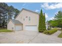 Side view of home with attached garage and large driveway and landscaped yard at 110 Village Green Cir, Tyrone, GA 30290