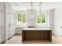 Bright kitchen with white cabinets, a wooden island, and modern lighting fixtures, complemented by stainless steel appliances at 11548 Serenbe Ln, Chattahoochee Hills, GA 30268