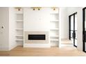 Bright living room showcasing a fireplace with built-in shelving and glass doors leading to the exterior at 11548 Serenbe Ln, Chattahoochee Hills, GA 30268