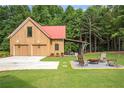 Spacious outbuilding with a red roof, garage doors, and cozy fire pit area with seating at 12520 Celestine Way, Milton, GA 30075