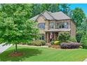 Beautiful home featuring a stone and brick exterior with lush landscaping and a well-maintained front lawn at 7045 Parrish Way, Cumming, GA 30040