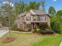 A beautiful house showcasing a manicured front yard, colorful landscaping, and a mix of brick and stone accents at 7045 Parrish Way, Cumming, GA 30040