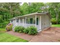 Charming single-story home with a covered front porch, manicured landscaping and a tree-lined backdrop at 4855 Brownsville Rd, Powder Springs, GA 30127