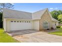 View of the home's side, showing the two-car garage and driveway on a sunny day at 129 Lakepointe Ct, Stockbridge, GA 30281