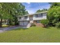 Split-level home featuring a two-car garage, brick accents, and a lush green lawn surrounded by trees at 3929 Emerald Springs Ct, Decatur, GA 30035