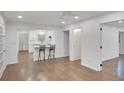 Open-concept living area with hardwood floors connecting to a modern white kitchen with a breakfast bar and bar stools at 4536 Mountain Creek Ne Dr, Roswell, GA 30075