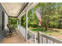 Inviting front porch featuring a chair, American flag, and serene views of the surrounding greenery at 588 Peachtree Se Dr, White, GA 30184