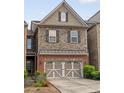 Two-story townhome featuring brick and stone facade, well-maintained landscaping, and a two-car garage at 690 Cobblestone Creek Ln, Mableton, GA 30126