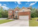 Two-story brick home featuring an attached garage, lush landscaping, and a spacious driveway at 1934 Acorn Ln, Dacula, GA 30019