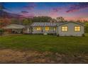 Charming single-story home with a covered porch, white siding, and a spacious front yard at dusk at 1871 Weems Rd, Locust Grove, GA 30248