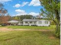 Charming single-story home with a covered porch, white siding, and a spacious front yard at 1871 Weems Rd, Locust Grove, GA 30248
