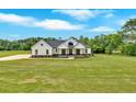 Expansive lawn showcases this modern farmhouse's elegant facade under a bright sky at 300 Eminence Peak, Rydal, GA 30171