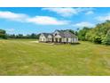 Aerial view of a modern farmhouse with a wide lawn and lush greenery surrounding it at 300 Eminence Peak, Rydal, GA 30171