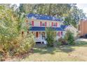Charming two-story home with red shutters, a white porch, and mature trees at 4092 Deerbrook Sw Way, Lilburn, GA 30047