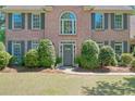 Close up of the home's brick front facade featuring the gray front door and manicured landscaping at 630 Silverberry Ln, Sugar Hill, GA 30518