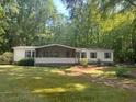 Quaint single-story home with a screened-in porch, surrounded by a lush green lawn and mature trees for privacy at 148 Boogers Hill Rd, Oxford, GA 30054